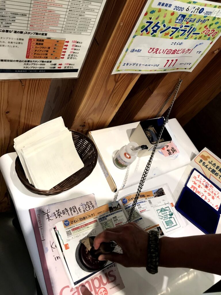 「道の駅びえい白金ビルケ」のスタンプを押す様子とスタンプ台周辺の備品