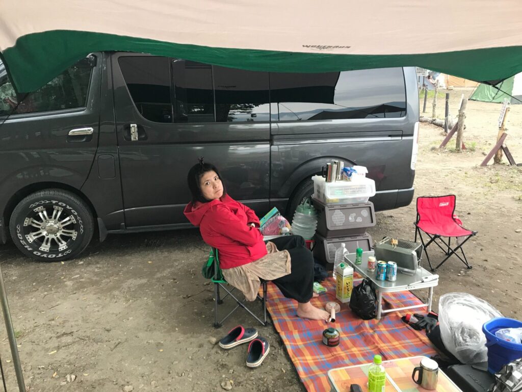 タープの下で椅子に座り、車中泊を楽しむ