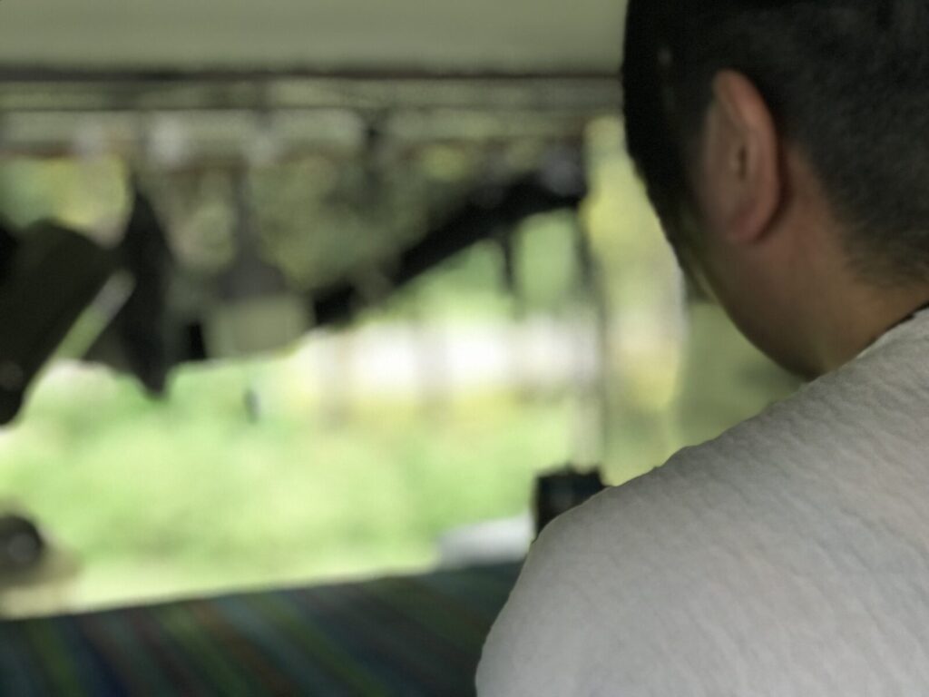 車内でくつろぎながら外を眺める男性の後ろ姿、緑あふれる景色