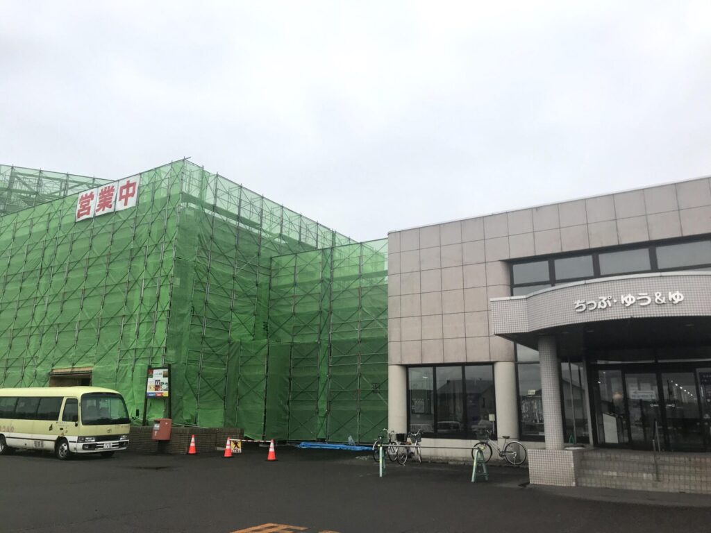 緑の足場に覆われたちっぷ・ゆう&ゆ、営業中の看板あり