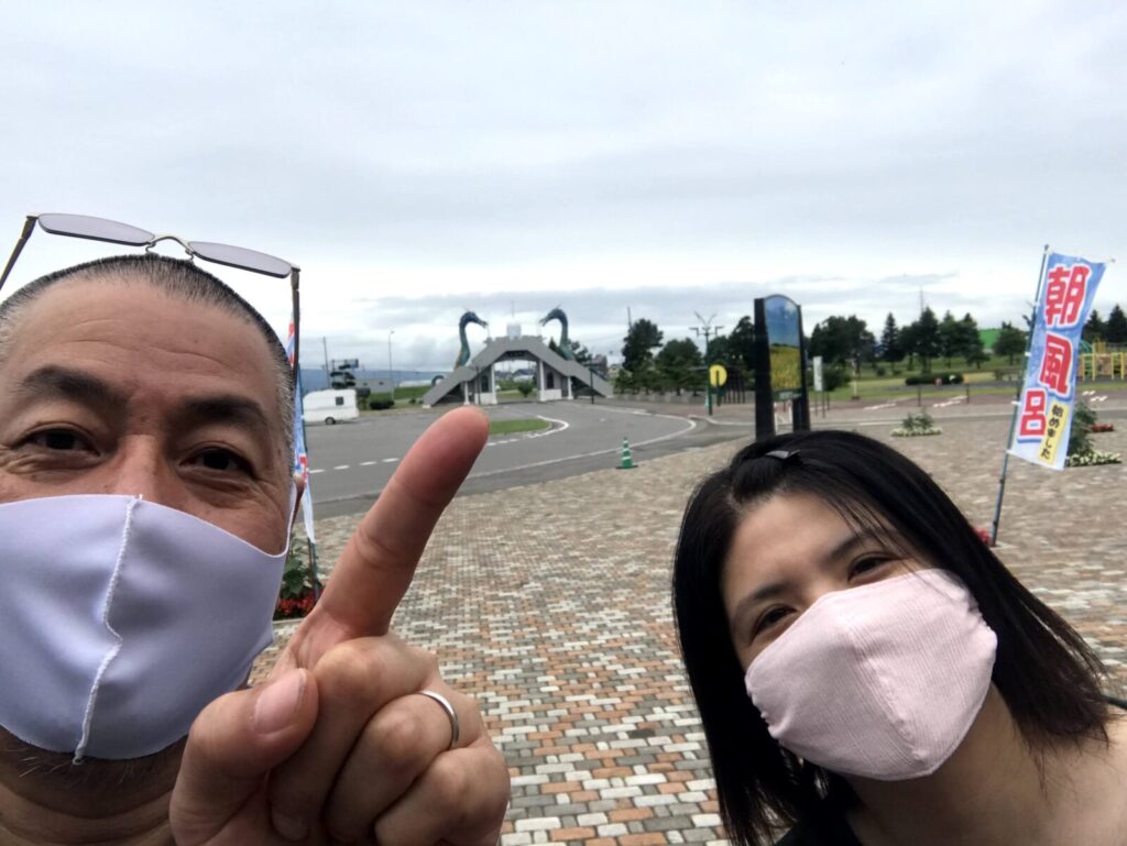 2人の男女が北竜門の前で笑顔で記念撮影し、男性が竜を指さしている様子