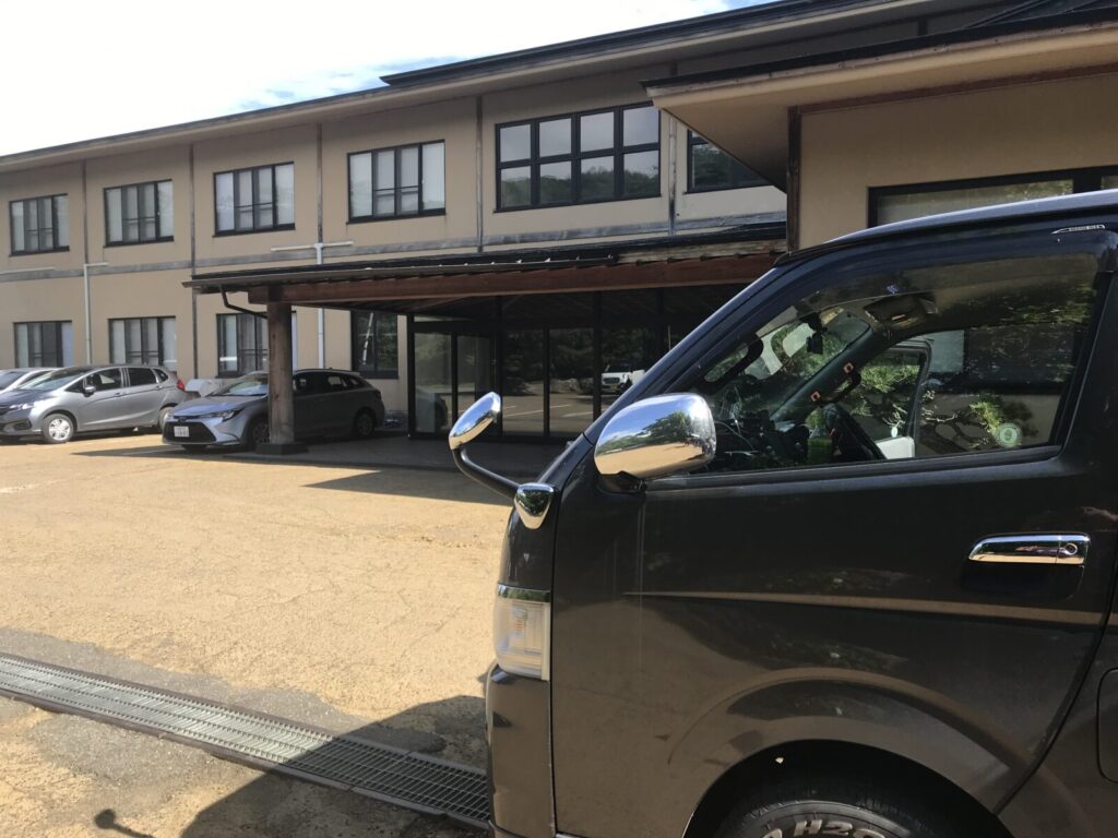 駐車場に停められたキャンピングカーと宿外観