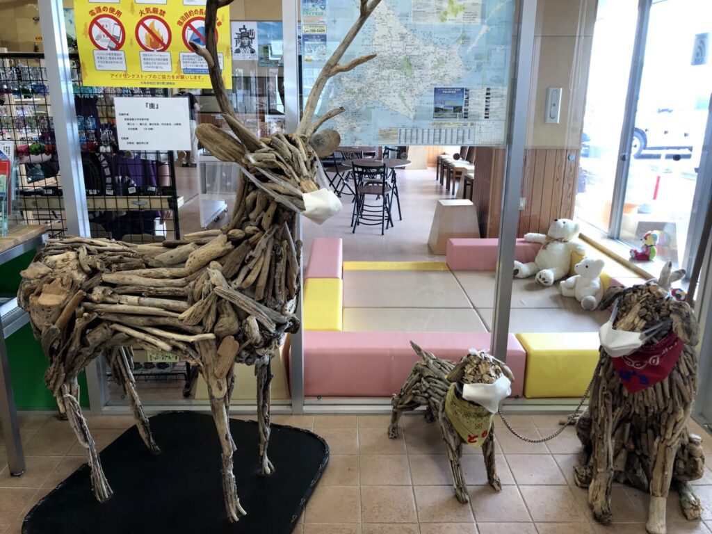 道の駅オスコイ!かもえないに展示されているマスク姿の流木アート作品(鹿と犬)