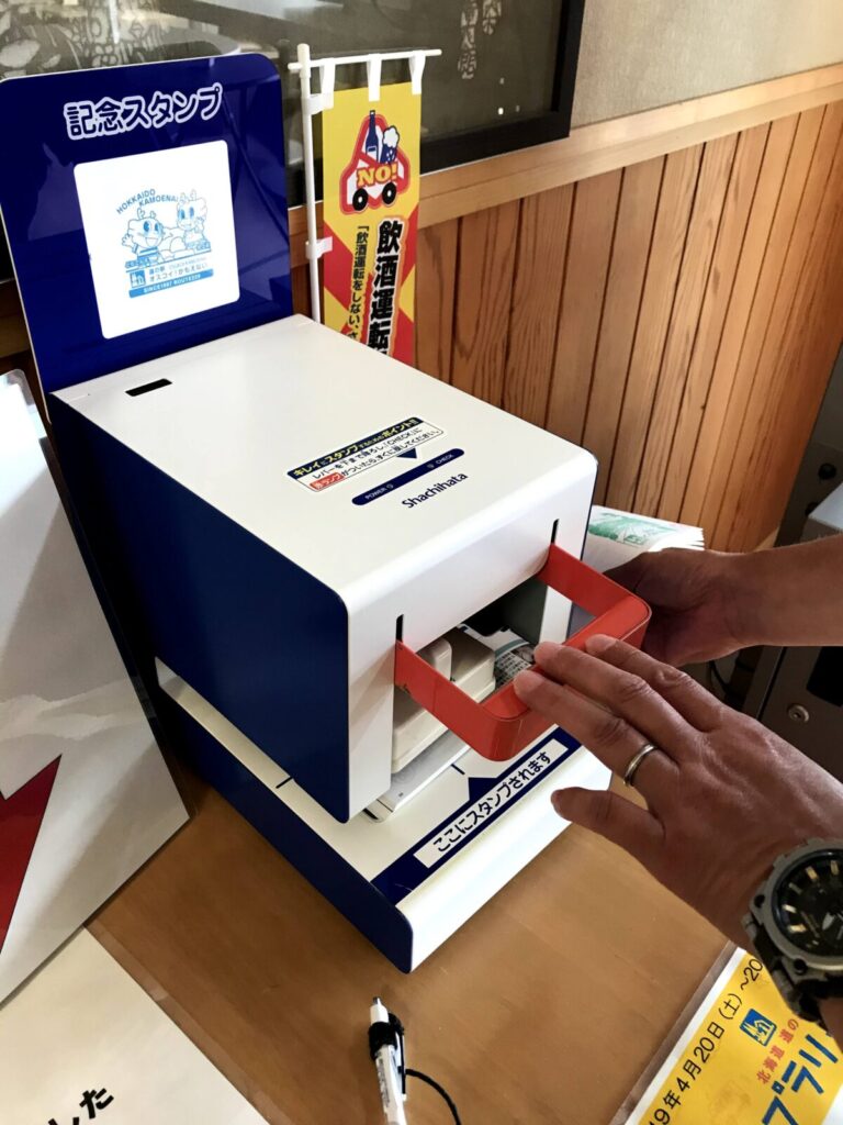 道の駅オスコイ!かもえないの自動スタンプ機にスタンプ帳をセットして押している様子