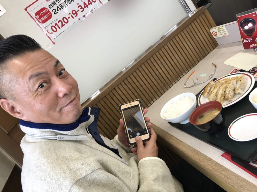2017年、「みよしの」でぎょうざ定食を前に笑顔を見せる男性の写真