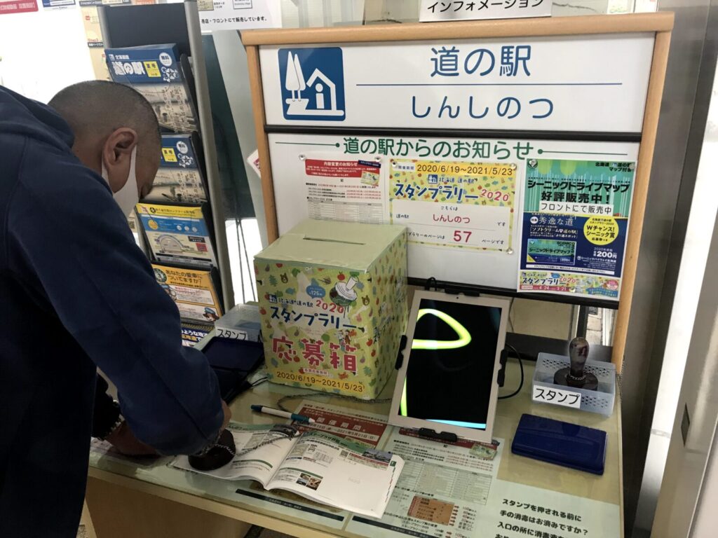 スタンプ帳に道の駅しんしのつのスタンプを押す男性の様子