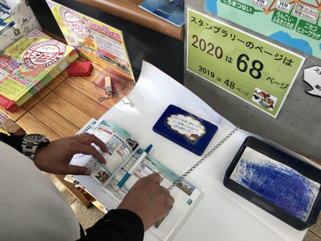 スタンプラリー帳に押印する様子と「2020年は68ページ」の案内