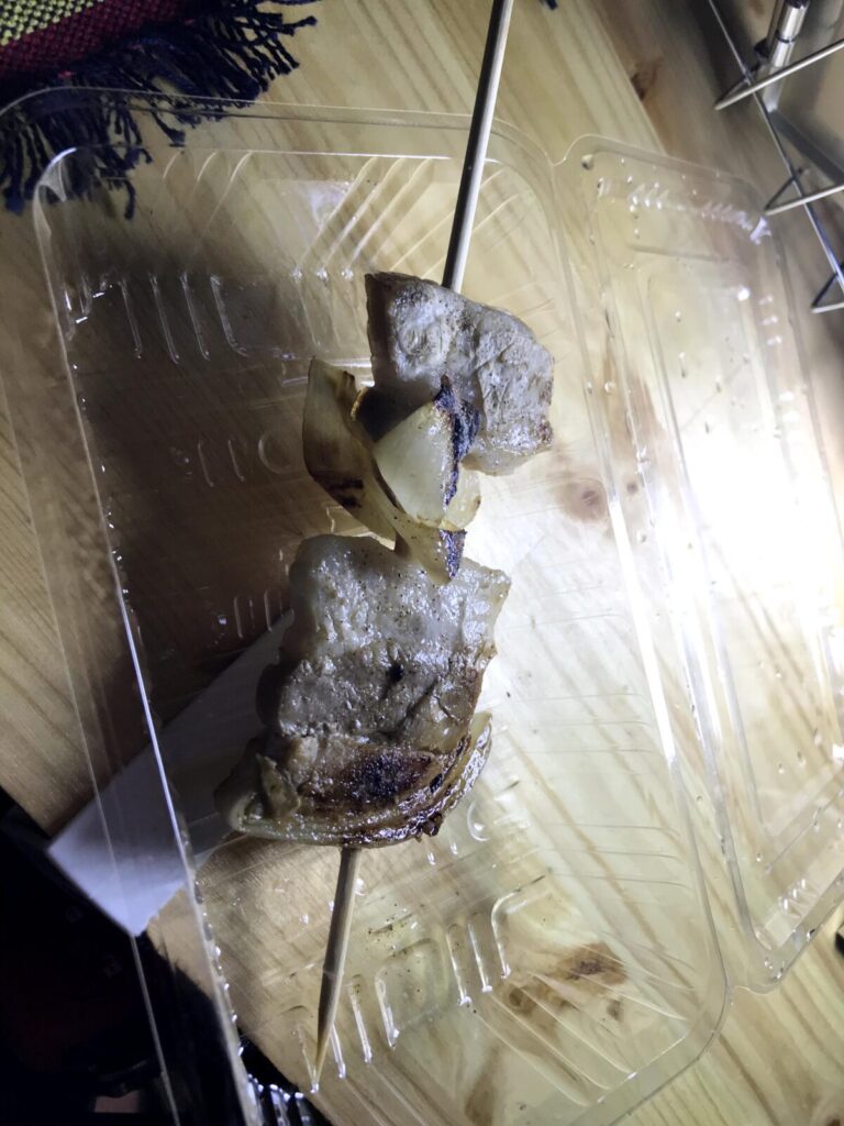 焼き目がついた豚肉と玉ねぎの串焼き(豚串)をパックに入れた様子