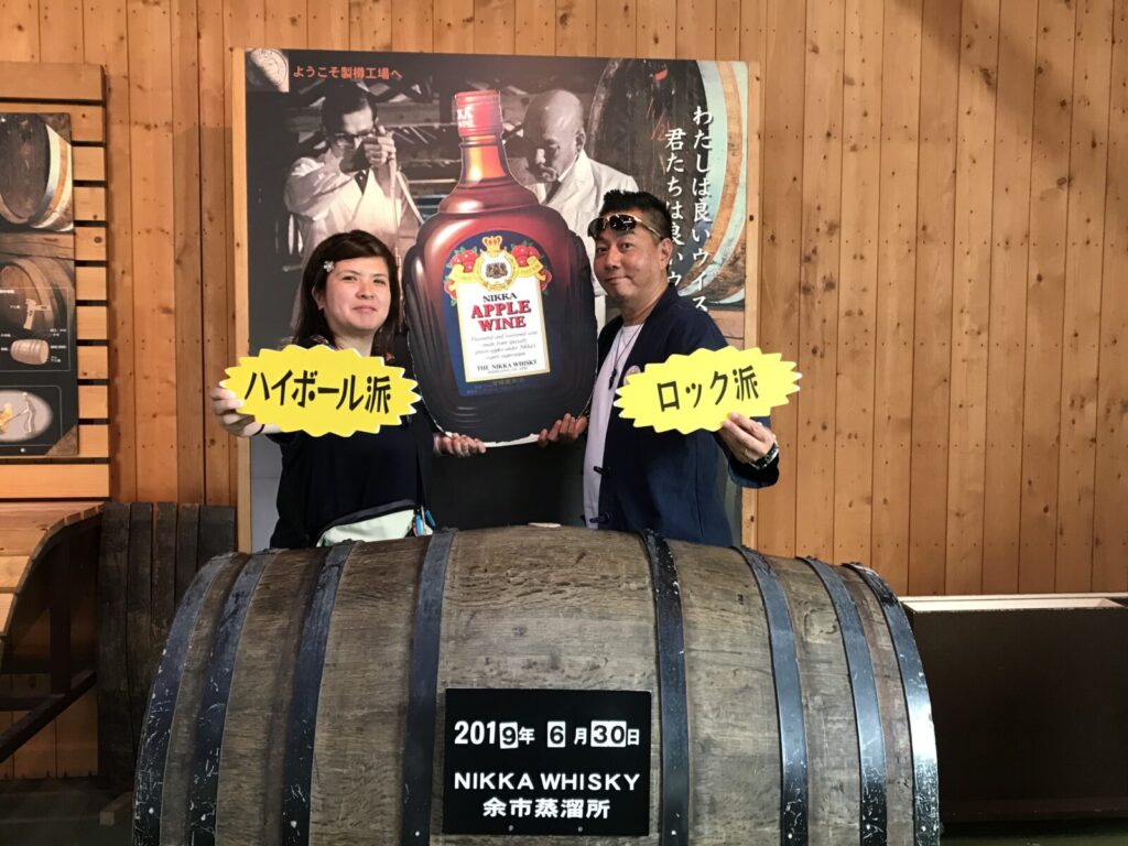 アップルワインの看板前でハイボール派とロック派に分かれる夫婦
