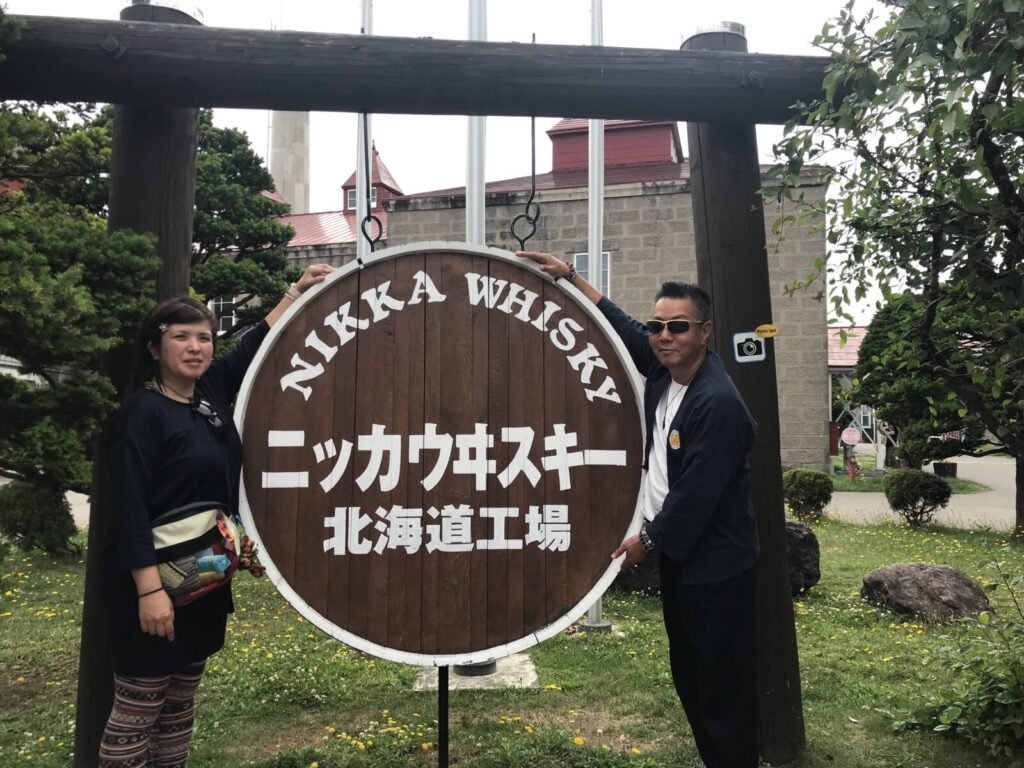 ニッカウヰスキー北海道工場の樽型看板と記念撮影する夫婦