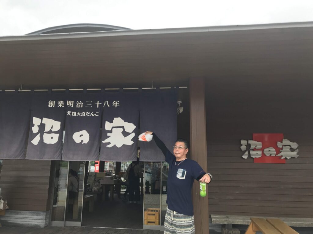 「沼の家」と書かれたのれんの前でポーズをとる男性