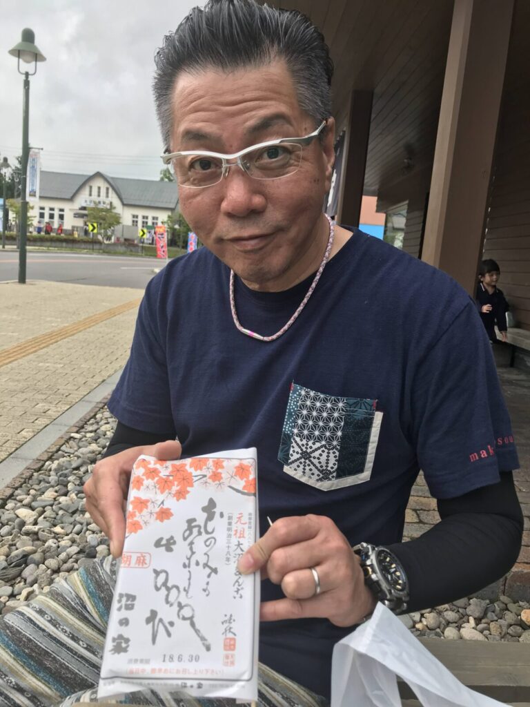 男性が「沼の家」の元祖大沼だんごを手に持っている様子