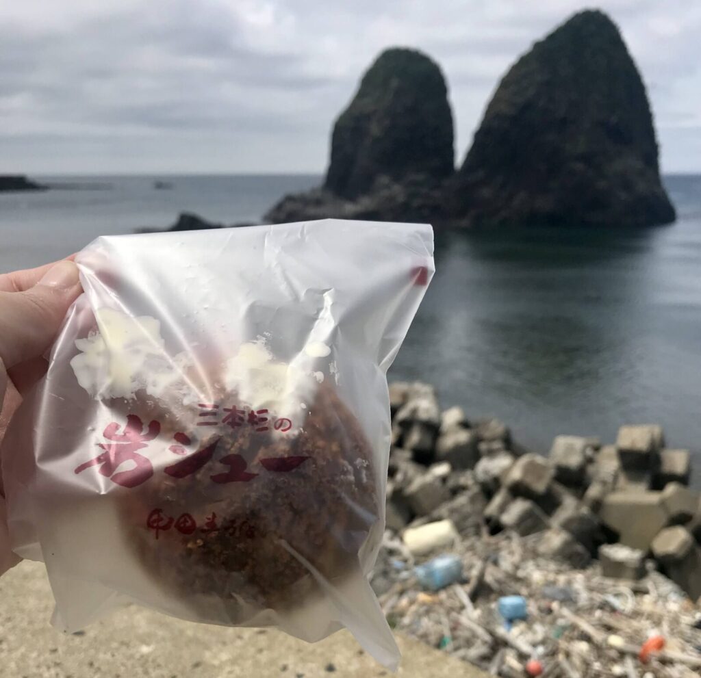 三本杉岩を背景に持ち上げた岩シュー