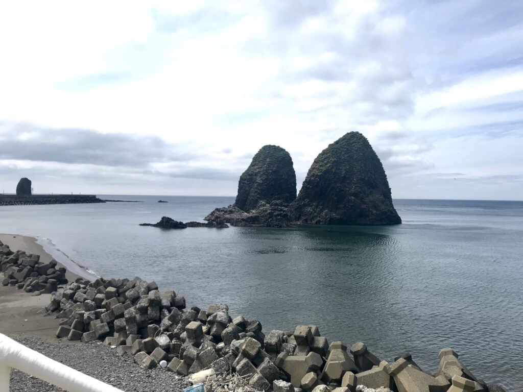 穏やかな海に浮かぶ三本杉岩(夫婦岩)の風景