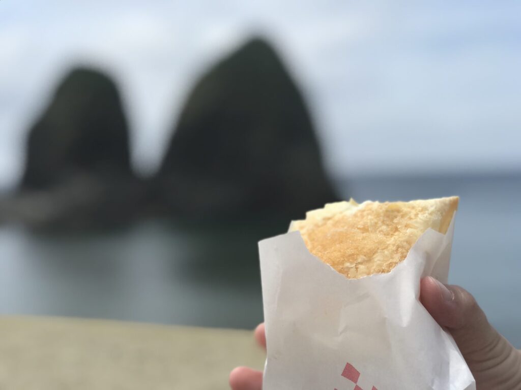 半分食べかけのサクサクカスタードと三本杉岩の背景
