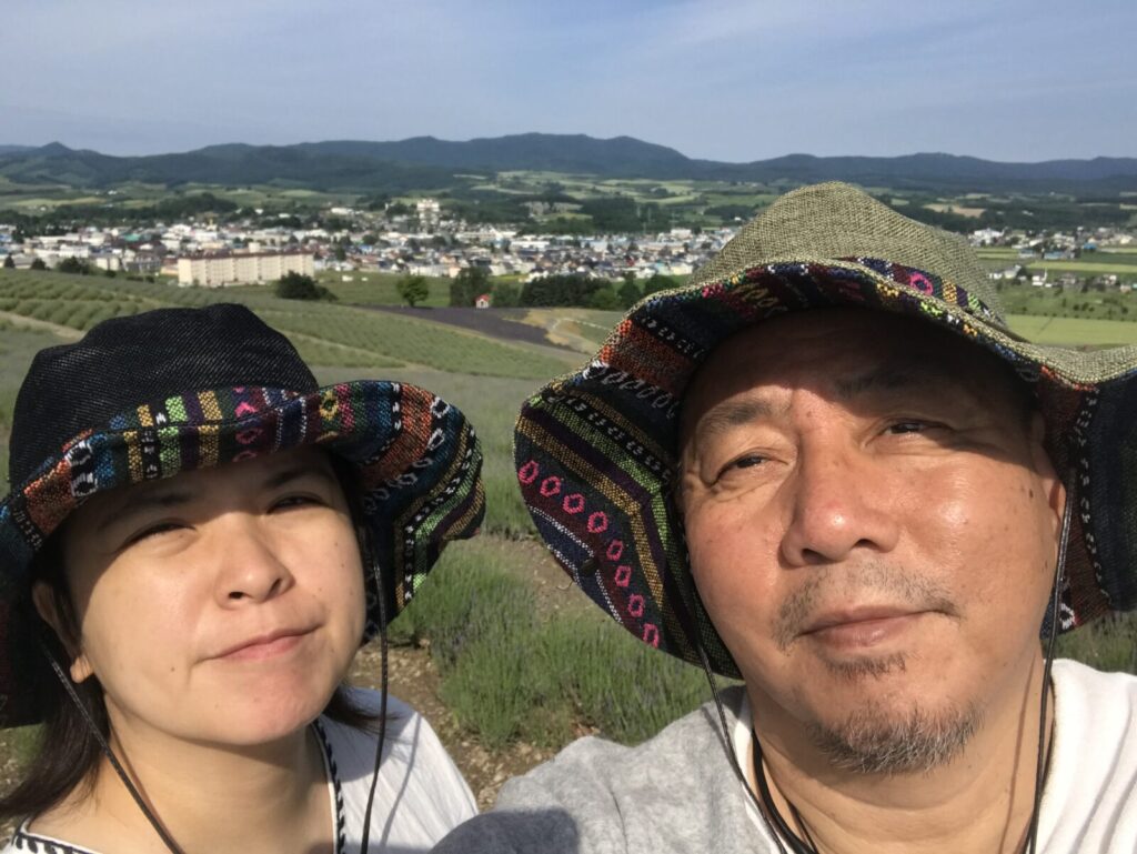 カラフルな帽子をかぶった夫婦がラベンダー畑を背景に自撮りする様子