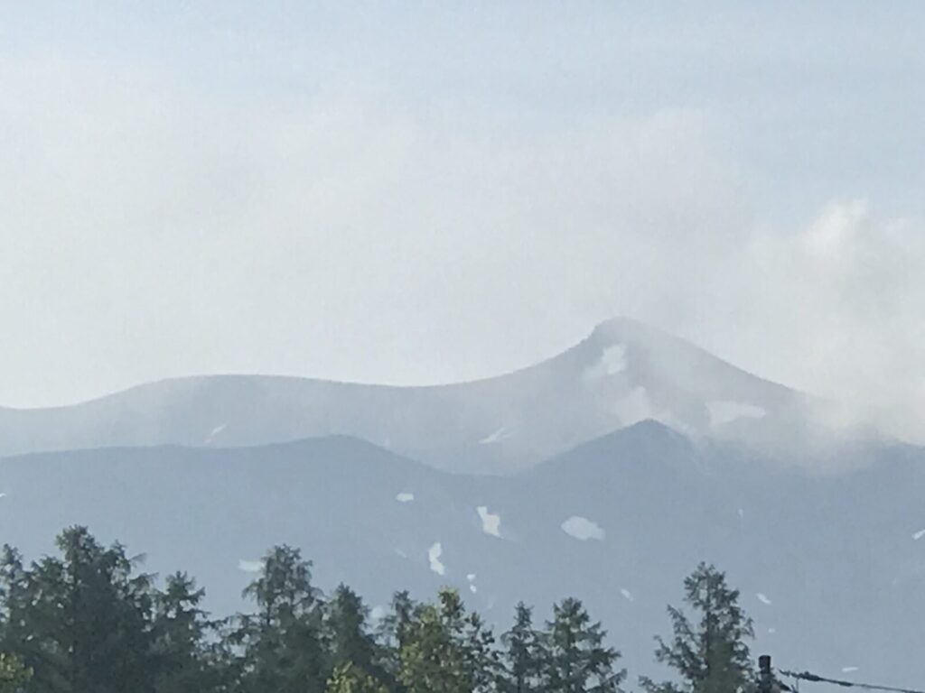 薄い雲の中から姿を見せる旭岳の山並みをズームで撮影。