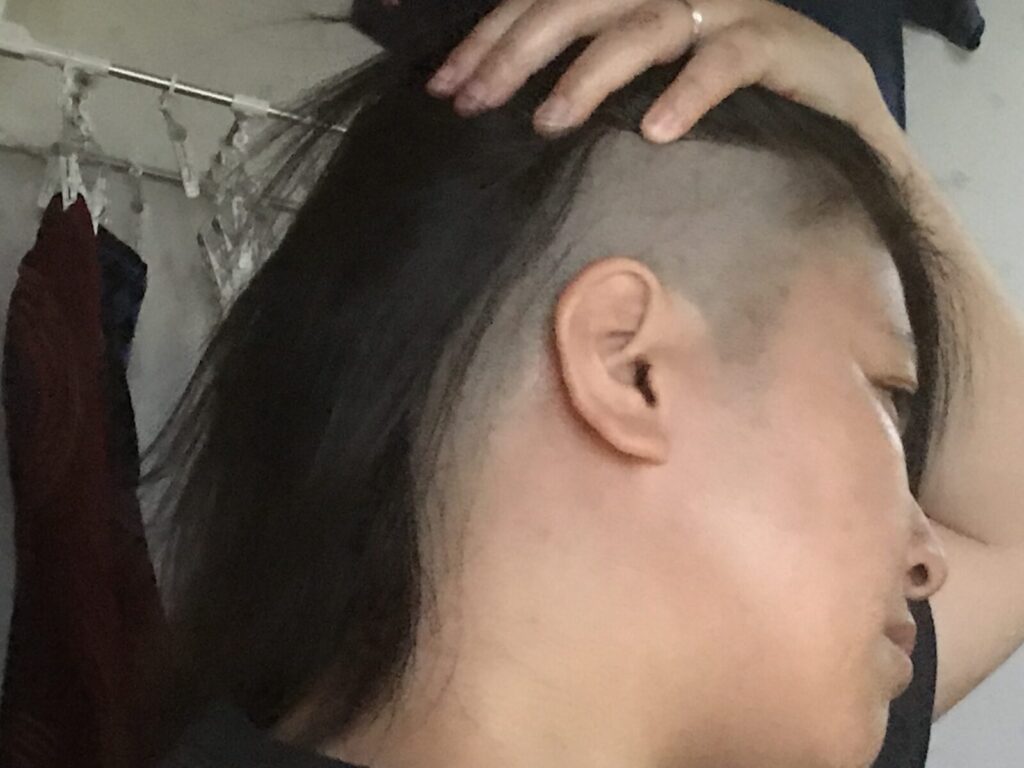 サイドを刈り上げた髪型を見せる女性の横顔