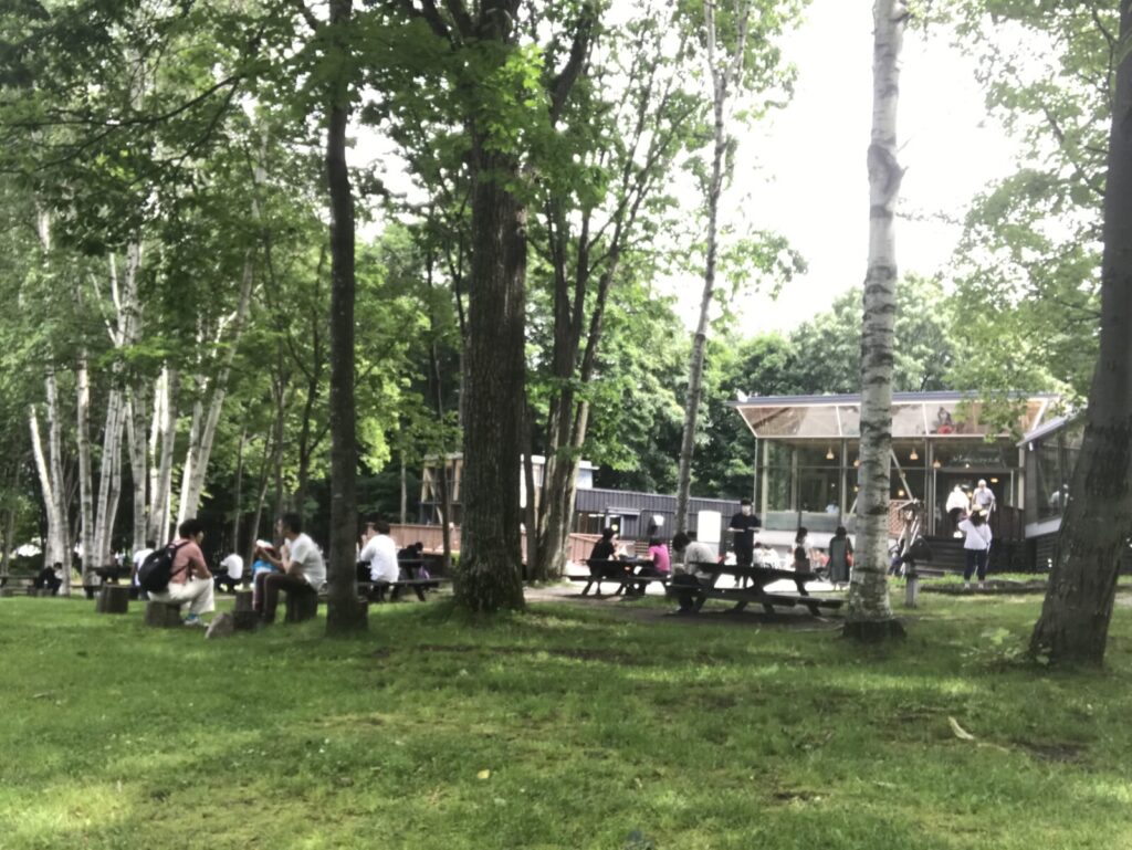 富良野チーズ工房のカフェテラスで過ごす人々と白樺の風景