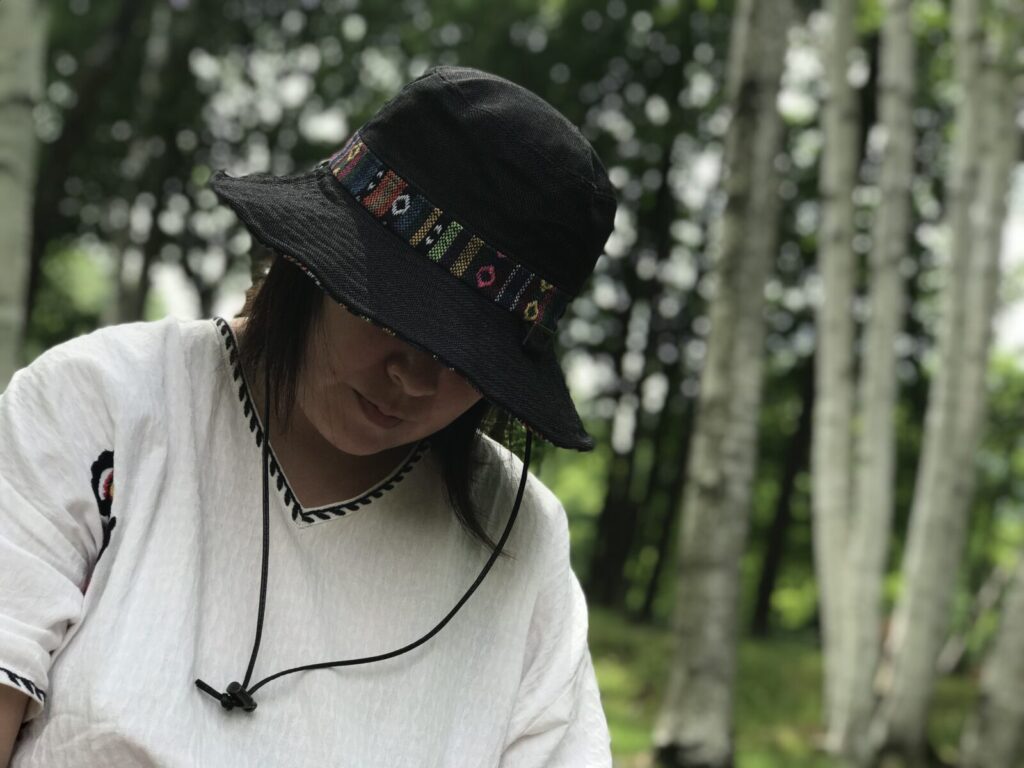 富良野チーズ工房の森の中で帽子をかぶってくつろぐ女性の様子