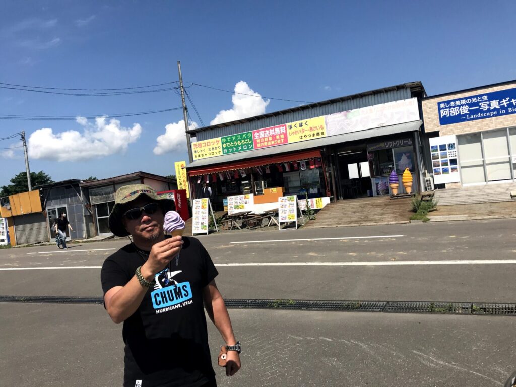 富良野でラベンダーソフトクリームを持つ男性と売店前