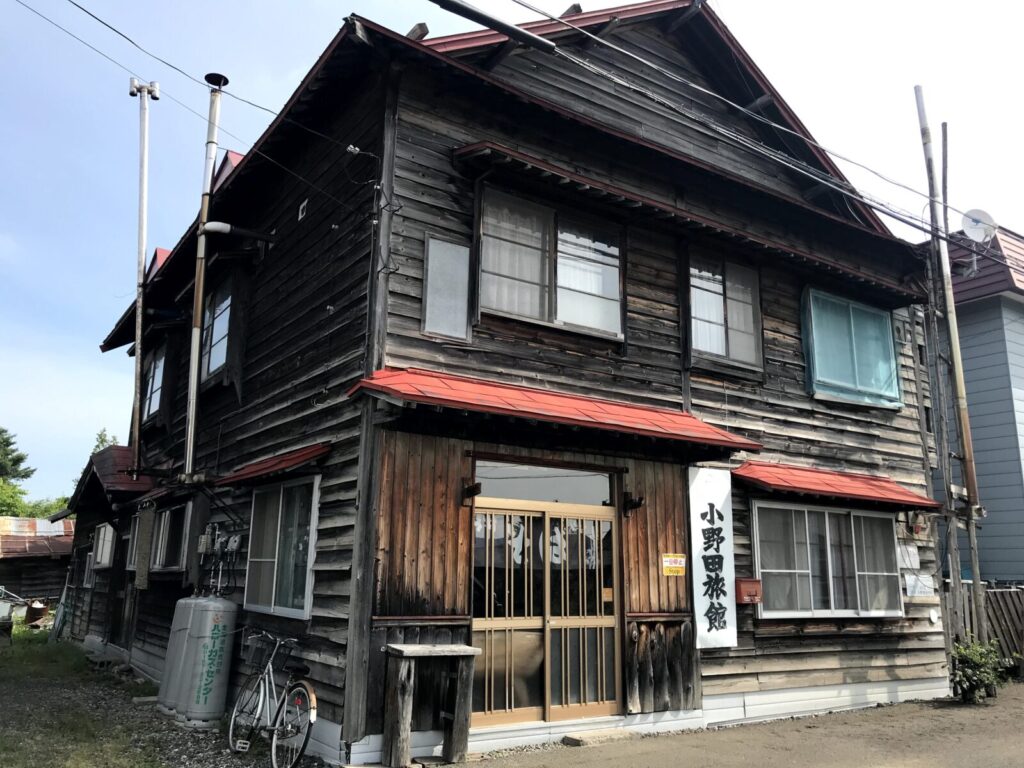 赤い屋根と木造外壁が特徴的な「小野田旅館」の外観。昭和の趣を残すレトロな建物。