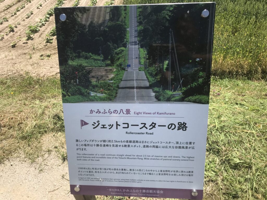 ジェットコースターの路を紹介する案内看板と畑の風景(上富良野)