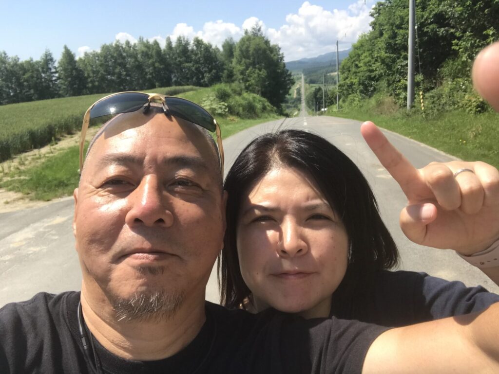 ジェットコースターの路を背景にした夫婦の自撮り写真(上富良野)