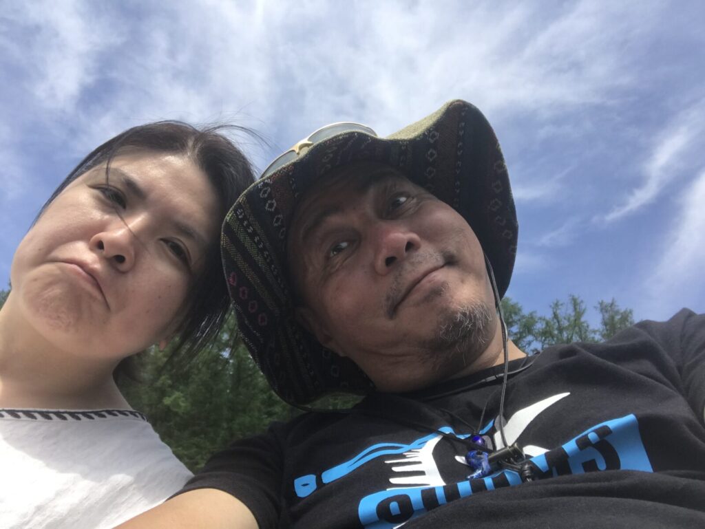 青空の下、楽しい表情で自撮りする夫婦の写真