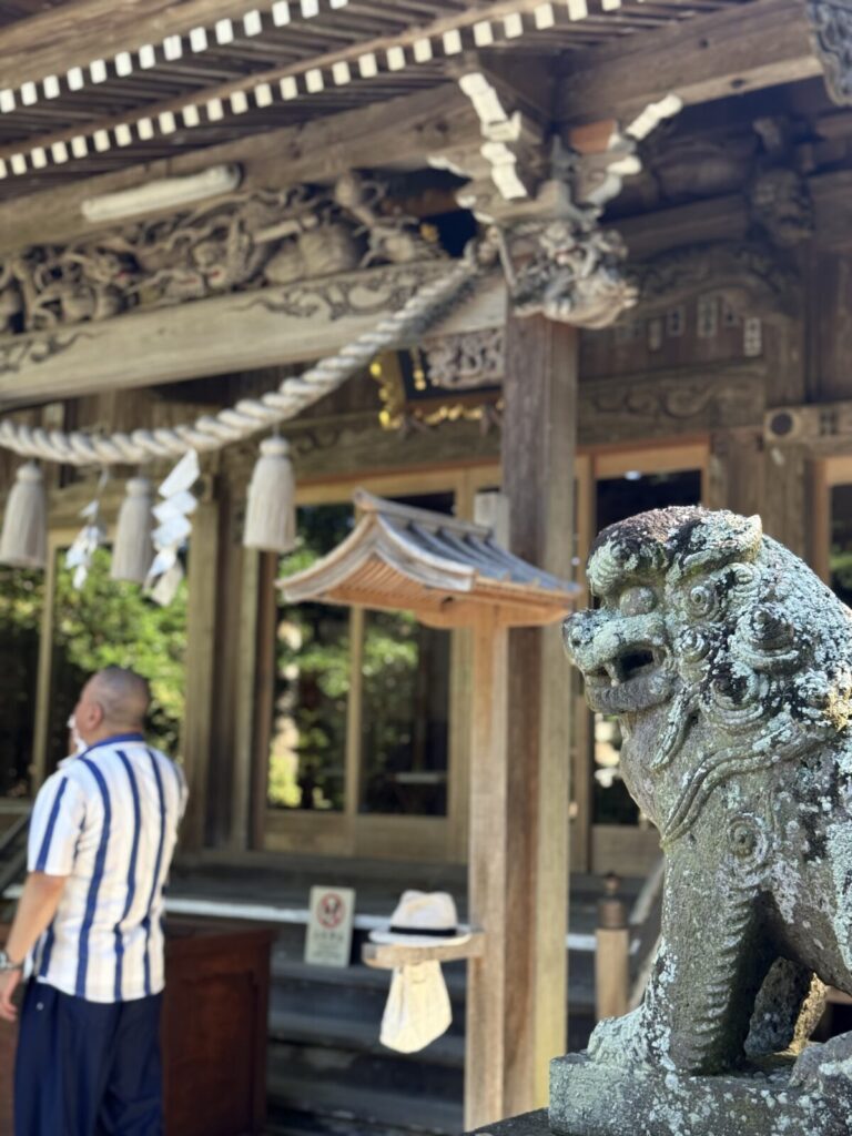 狛犬の石像と参拝する男性、勝浦の神社の様子