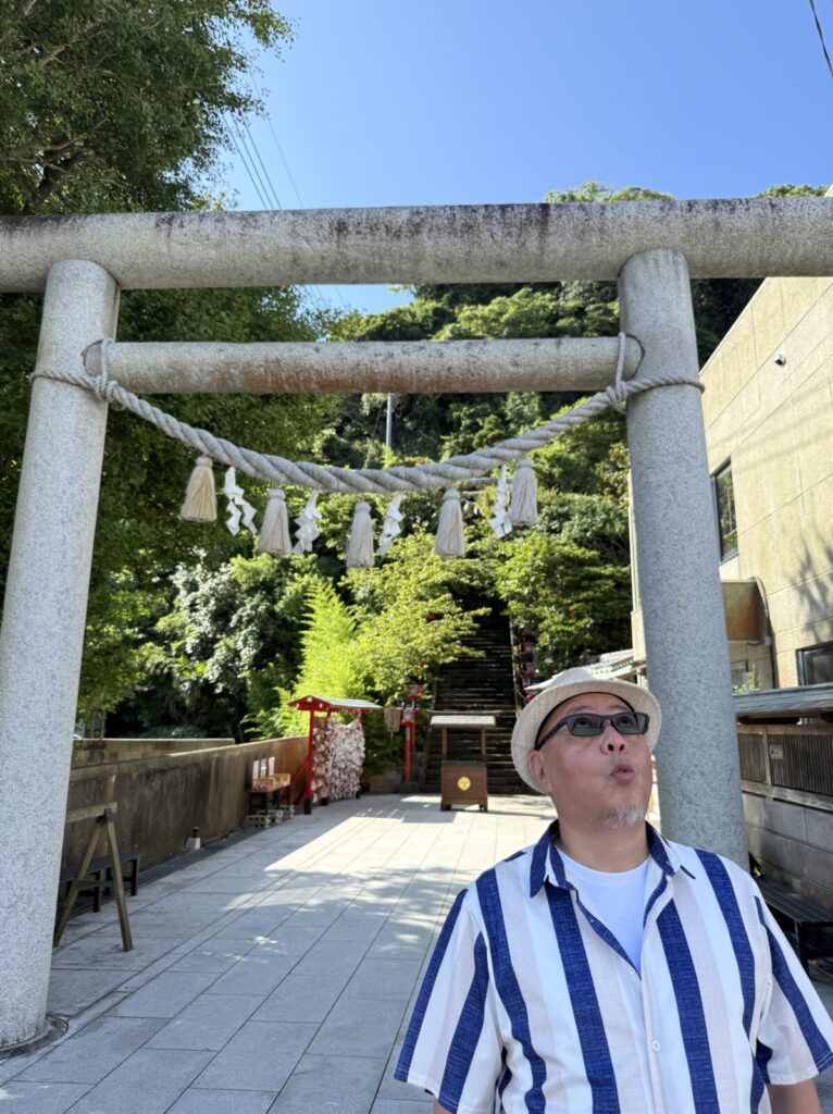 遠見岬神社の鳥居前で空を見上げる男性