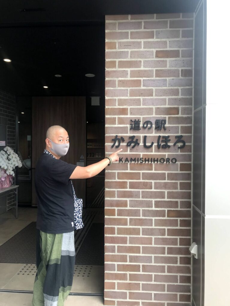 道の駅かみしほろの入口でレンガ壁の看板を指さす男性