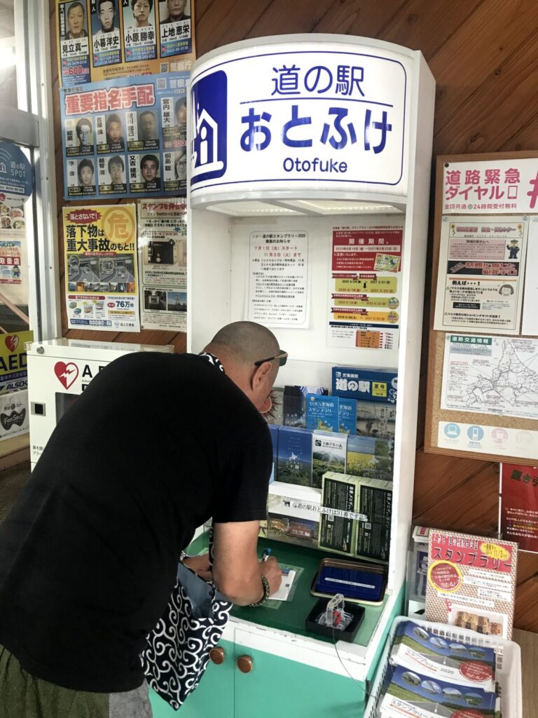 道の駅おとふけのスタンプコーナーでスタンプ帳に記入する男性
