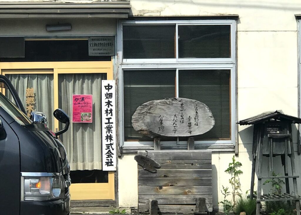 中畑木材工業の看板と木製の詩が刻まれたオブジェ

