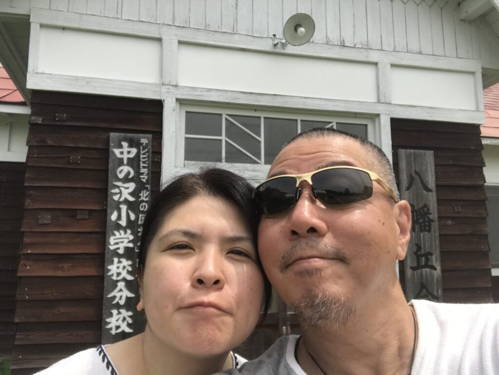旧中の沢小学校分校の前で記念撮影する夫婦