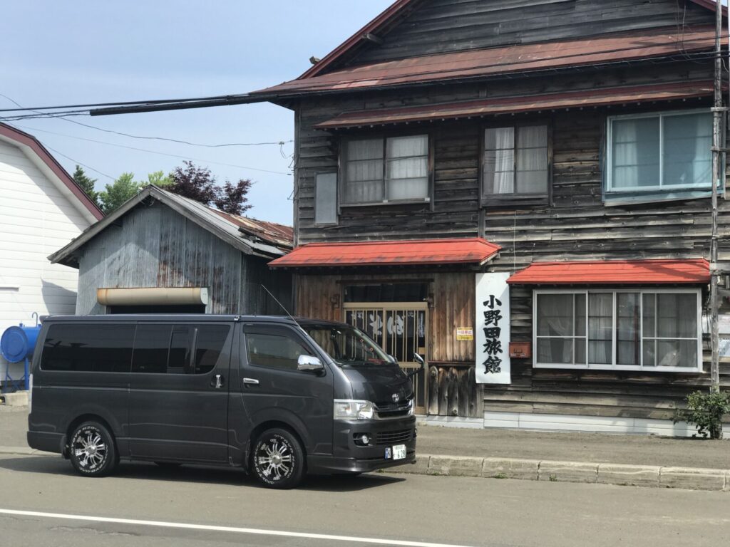 赤い屋根と木造外観が印象的な小野田旅館の前に停車するキャンピングカー