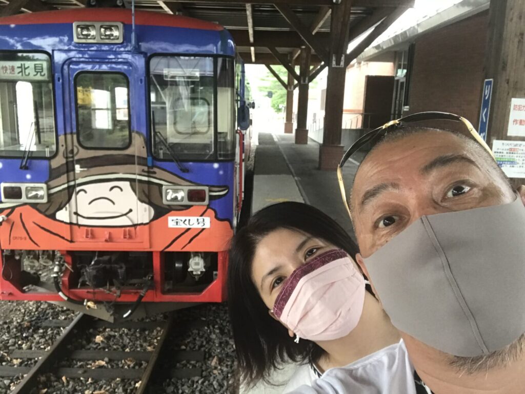 宝くじ号の前で撮影したマスク姿のツーショット記念写真
