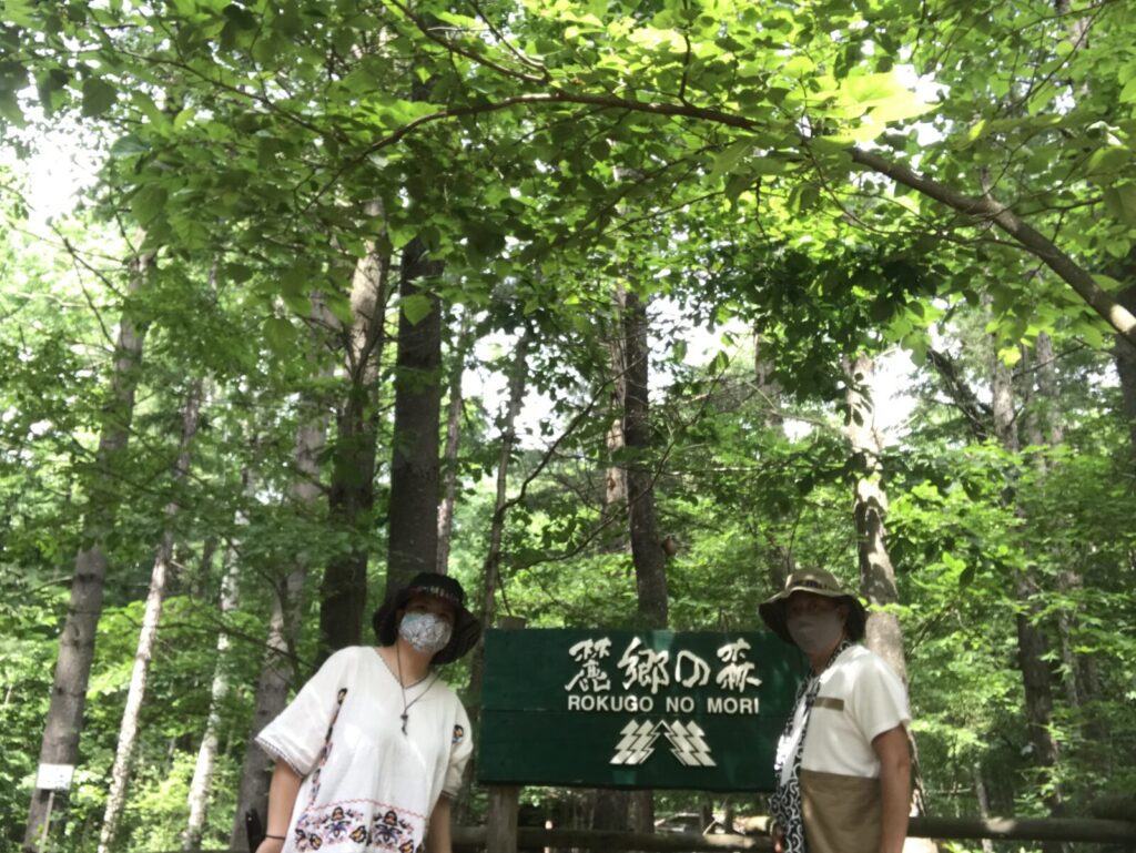 富良野の「麓郷の森」入口の看板の前で記念撮影する夫婦の写真
