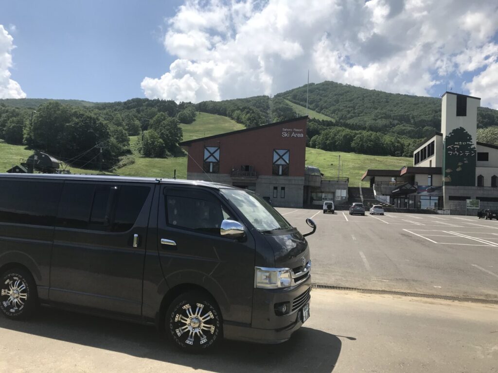 サホロベアマウンテン前の駐車場に停まるハイエースとスキー場の全景