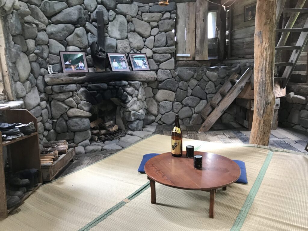 石造りの暖炉と畳の間に置かれたちゃぶ台と日本酒の瓶