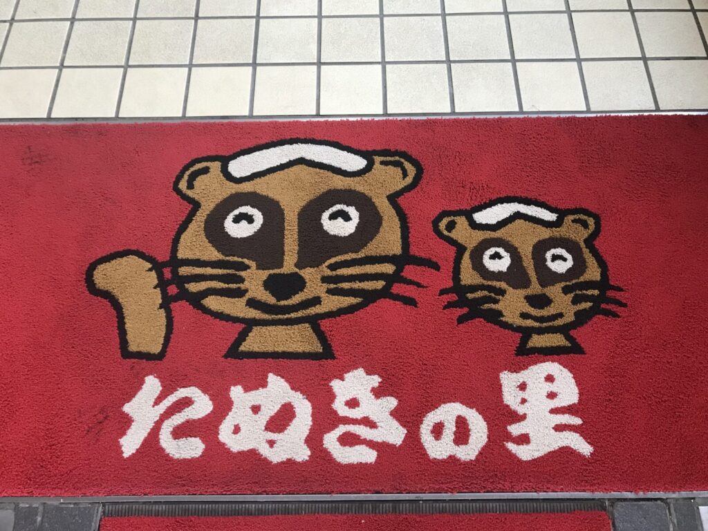 日帰り温泉たぬきの湯のたぬきキャラクターが描かれた玄関マット