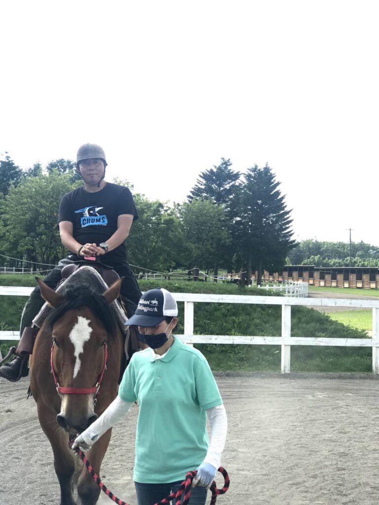 馬に乗って親指を立てる男性と付き添うスタッフ(うりまく乗馬体験)