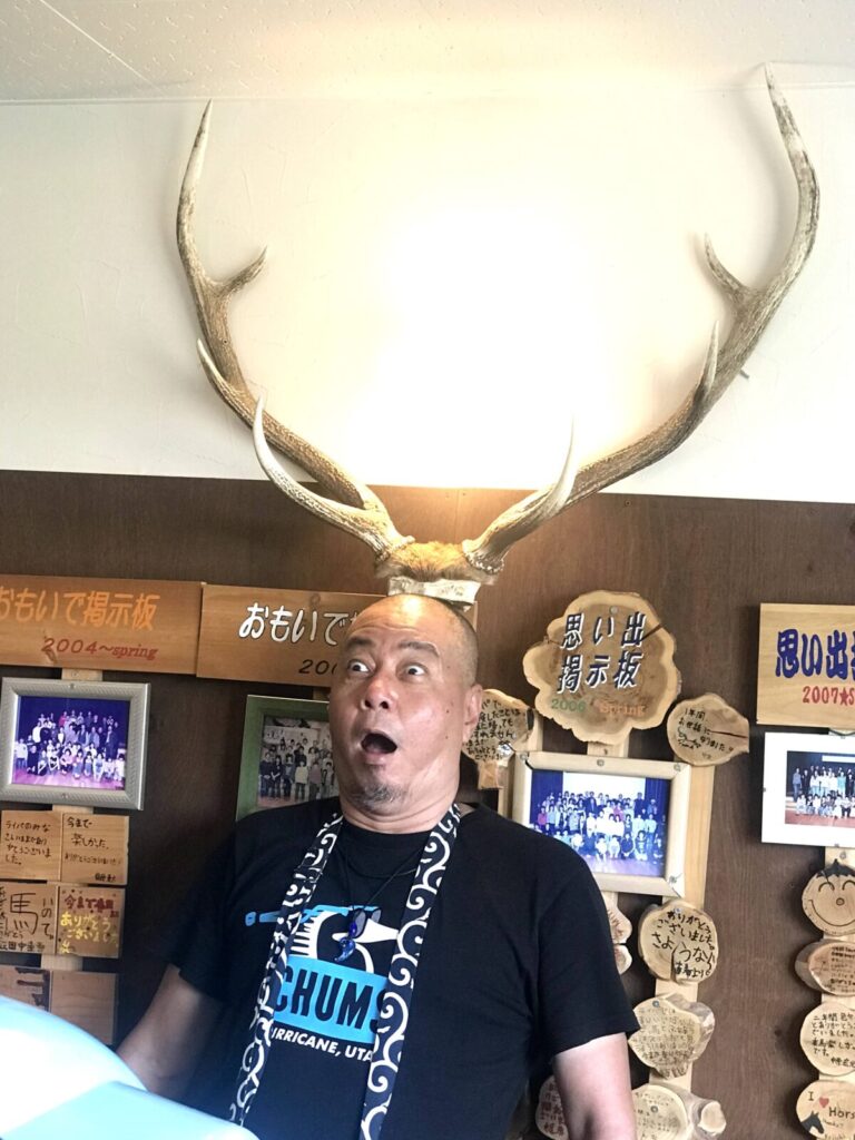 道の駅うりまくの思い出掲示板前で角が生えたような男性のポーズ