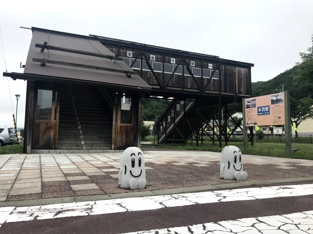 本別駅跡にある木造の跨線橋と、前に並ぶ笑顔の石像キャラクター
