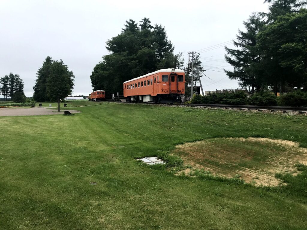 幸福駅跡地に展示されたオレンジ色の旧国鉄車両と芝生の広がる風景
