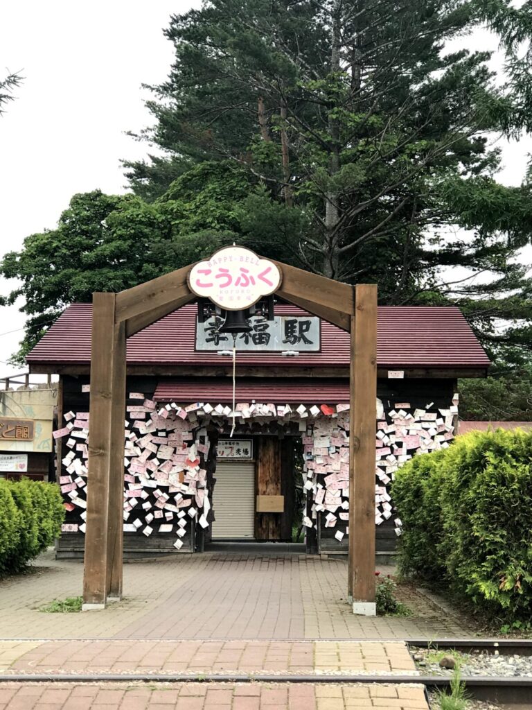 幸福駅の駅舎に貼られたたくさんの願い事と「ハッピーベル」のアーチ