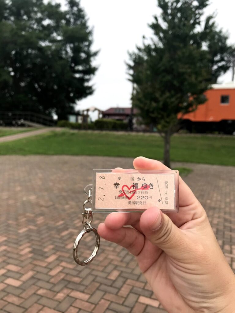 幸福ゆきの記念切符をデザインしたキーホルダーを手に持って撮影