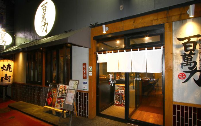 百萬力 北見本店の白い暖簾と木枠の戸がある入口