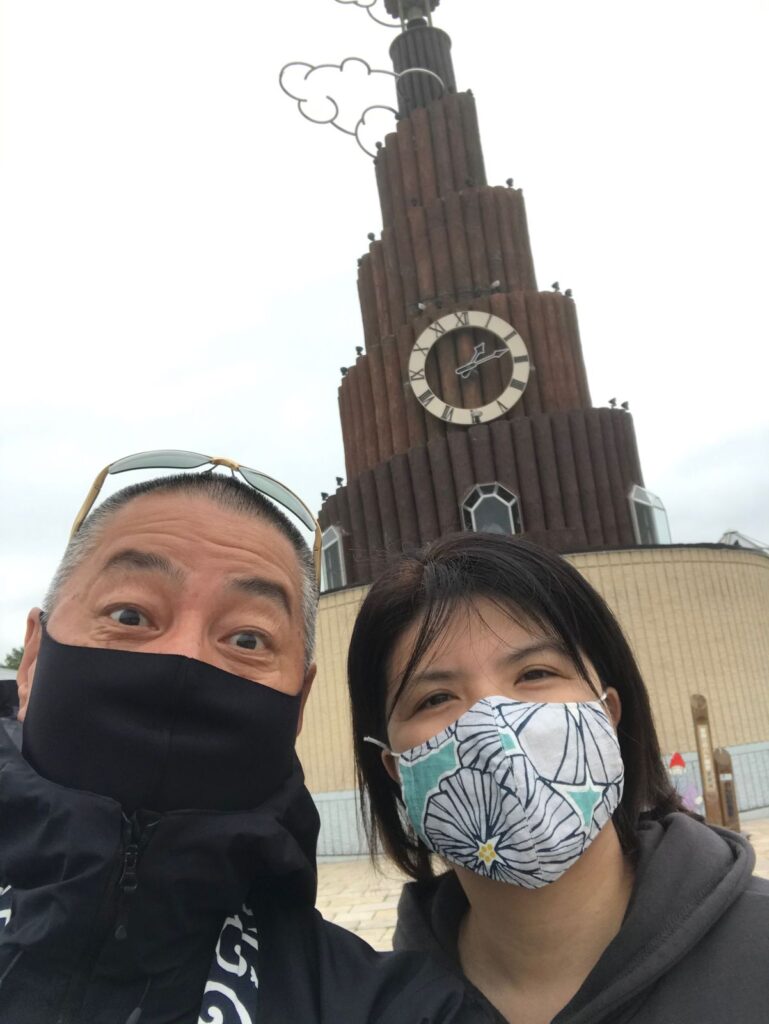 道の駅おんねゆ温泉の果夢林の時計塔の前で撮った、マスク姿のくま嫁と旦那の自撮り